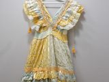 yellow and green dress hanging on a hanger against a white wall