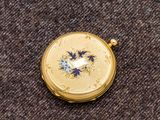 une petite montre de poche en or ornée de fleurs bleues