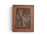 une plaque en bois représentant un coq sur un mur blanc