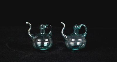 une paire de théières en verre vert sur fond noir