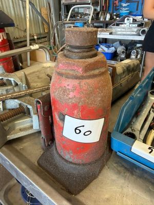 une grande bouteille rouge posée sur une table, sur laquelle figure le chiffre 6