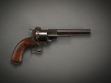 a close up of a revolver on a table with a gray background