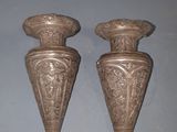 two silver vases sitting on top of a table next to each other