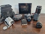 une table avec un appareil photo, un étui pour appareil photo, un objectif, un étui pour appareil photo, un étui pour appareil photo et un sac pour appareil photo