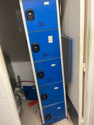 une photo représentant une rangée de casiers bleus dans des toilettes