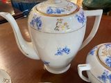 a table with a tea pot, cups, and saucers on it