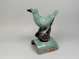 a small green bird sitting on top of a piece of wood