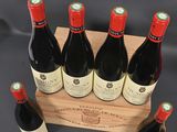 six bottles of red wine in a wooden crate on a black background