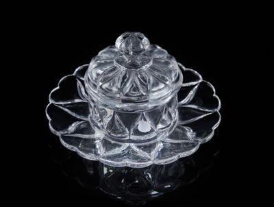 un récipient en verre transparent muni d'un couvercle, posé sur une assiette