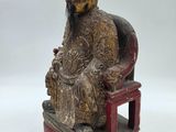 an old statue of a man sitting on a chair with a hat on