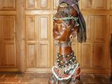 une statue représentant une femme assise sur un plancher en bois