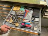 un tiroir rempli de fournitures scolaires et une personne tenant une paire de ciseaux