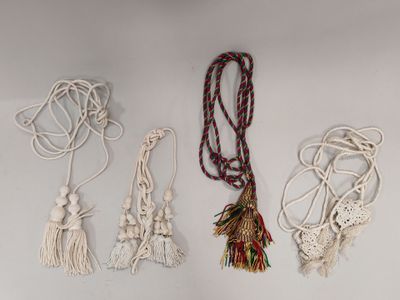 quatre colliers en macramé avec des pompons sur fond blanc