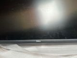 a dell laptop sitting on a bed with a white sheet on it