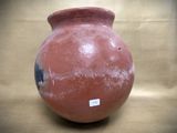 a red vase sitting on a table with a sticker on it