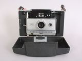a polaroid camera sitting in a case on a white surface
