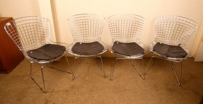 quatre chaises en acier chromé avec des coussins d'assise noirs dans une pièce
