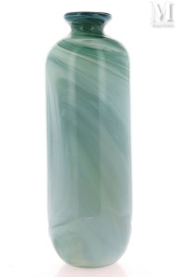 un vase vert posé sur une surface blanche