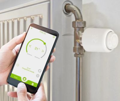 a person holding a smart phone in front of a radiator