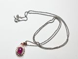 collier avec une pierre rose et une chaîne en argent sur fond blanc