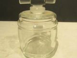 a small glass jar with a metal handle on a table