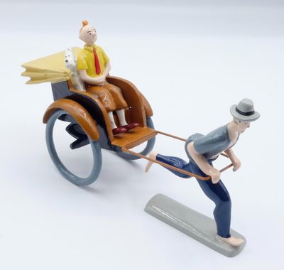 figurine représentant un homme tirant une calèche avec un chien
