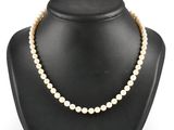 a white pearl necklace on a black mannequin