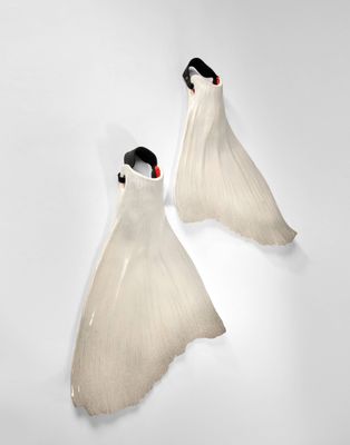 deux robes de mariée blanches accrochées à un mur dans une pièce blanche