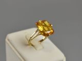 a close up of a ring with a yellow stone on top of a white box