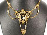 a gold necklace with pearls and flowers on a mannequin