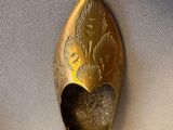 a gold spoon with a leaf design on it