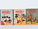 three mickey mouse books are lined up on a white surface