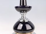 une photo d'un flacon de parfum en verre argenté et noir posé sur une surface transparente