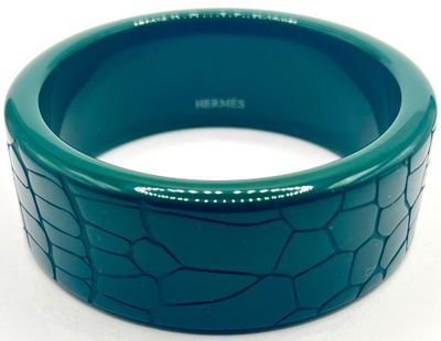 bracelet en plastique vert présentant une surface craquelée sur fond blanc