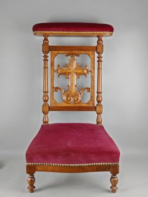 une vieille chaise avec une croix sur le dossier et une assise rouge