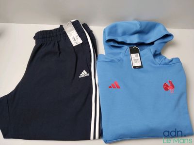 deux paires de survêtements Adidas et un sweat à capuche posés sur une table