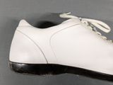 pair of white leather shoes with black soles on a gray surface