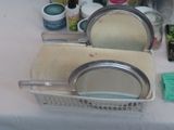 a sink with a mirror, soap, sponges, and other cleaning supplies on it