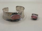 silver cuff bracelet with a pink stone set on a white surface