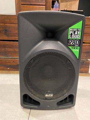 un gros plan sur une enceinte posée au sol, avec une boîte en arrière-plan