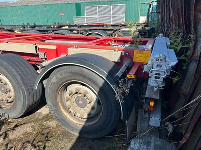 une remorque rouge garée à côté d'un arbre