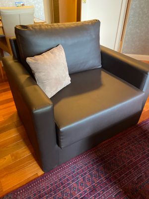 une chaise noire avec un coussin dessus, dans un salon