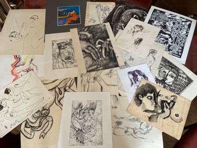 de nombreux dessins posés sur une table, à côté d'un ordinateur portable