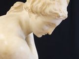 marble statue of a young boy kneeling on a marble base