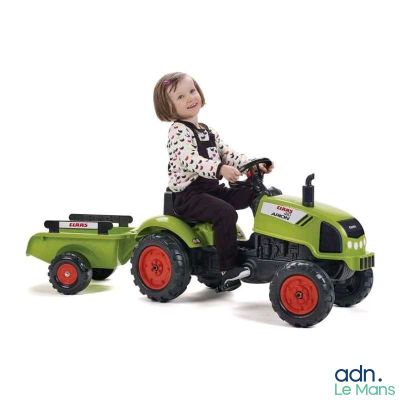 une petite fille assise sur un tracteur jouet