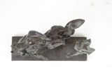 a statue of a woman laying down on a piece of wood