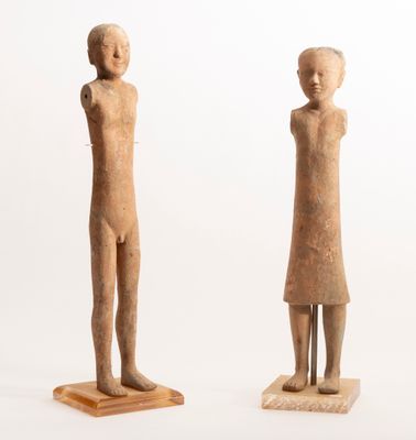 two figurines of a man and a woman standing on a wooden base