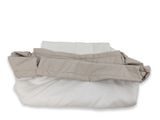 un tas d'oreillers et une couverture posés sur une surface blanche