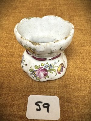 un petit vase blanc orné de fleurs, posé sur une table