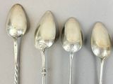 four spoons are lined up in a row on a table